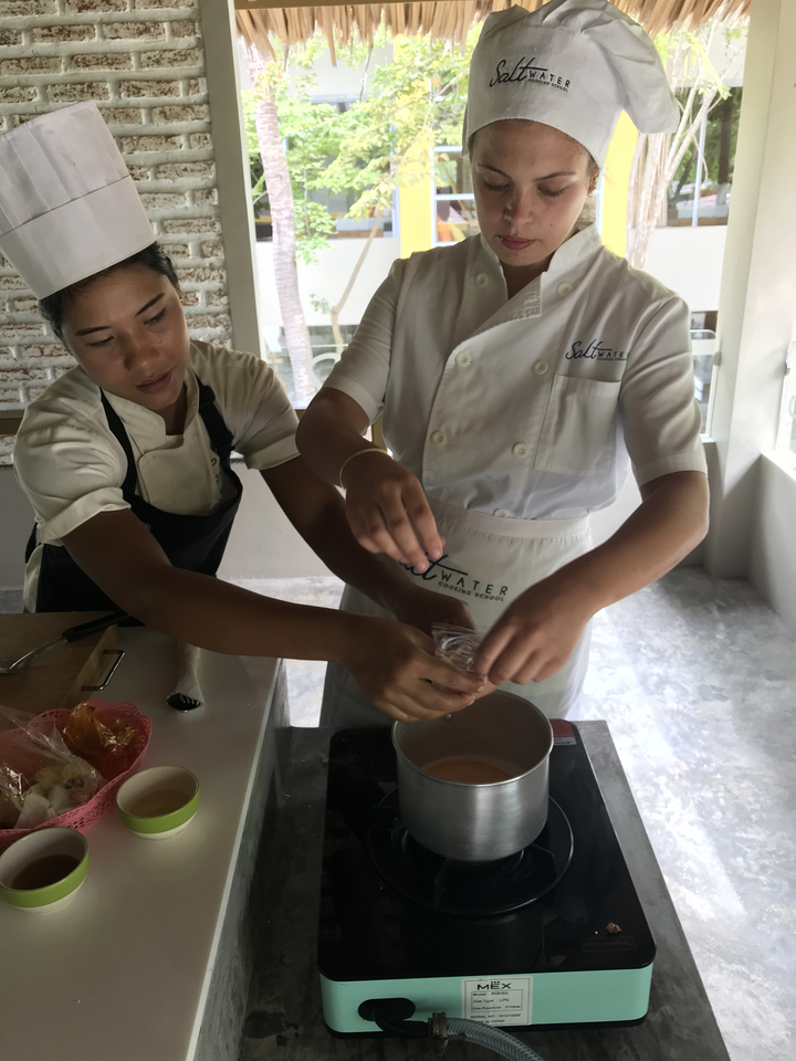 Two people preparing food in a cooking class.