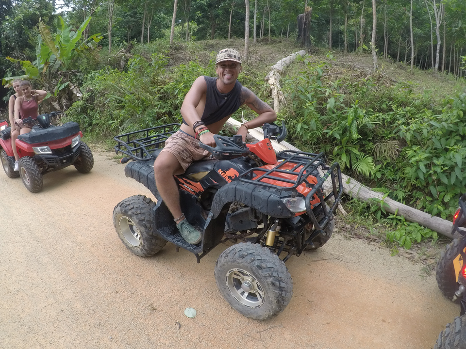 Person riding an ATV on a dirt path through greenery.