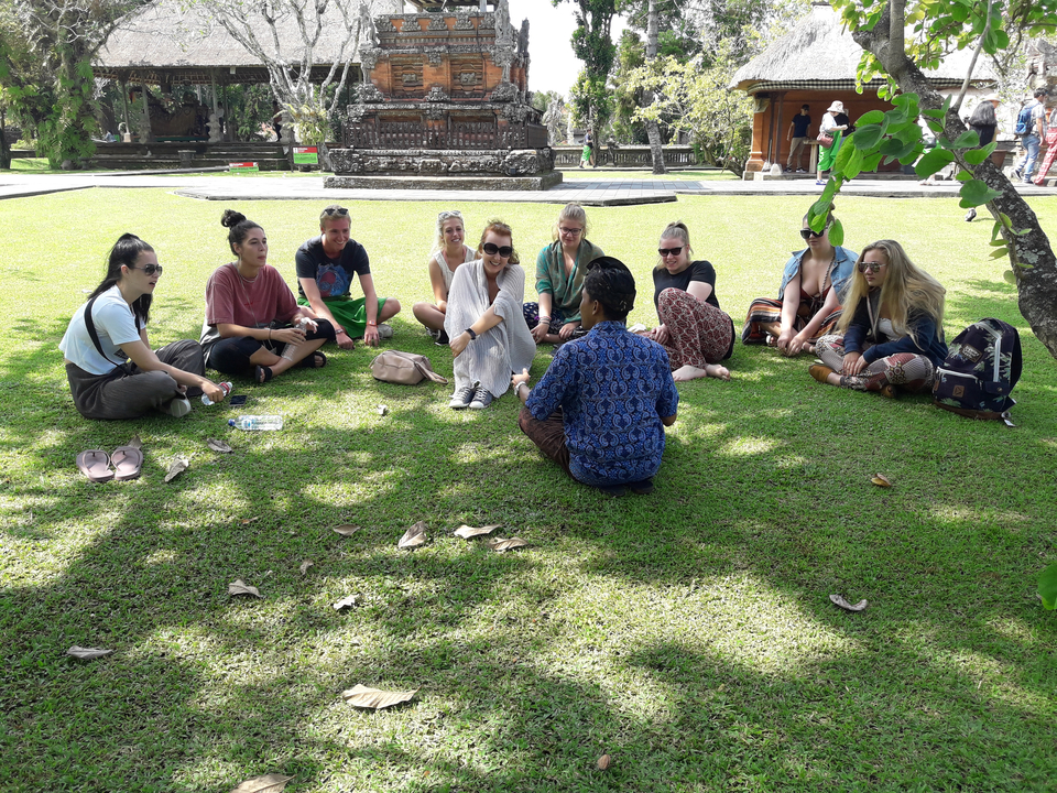 Group sitting on a lawn, engaged in a discussion.