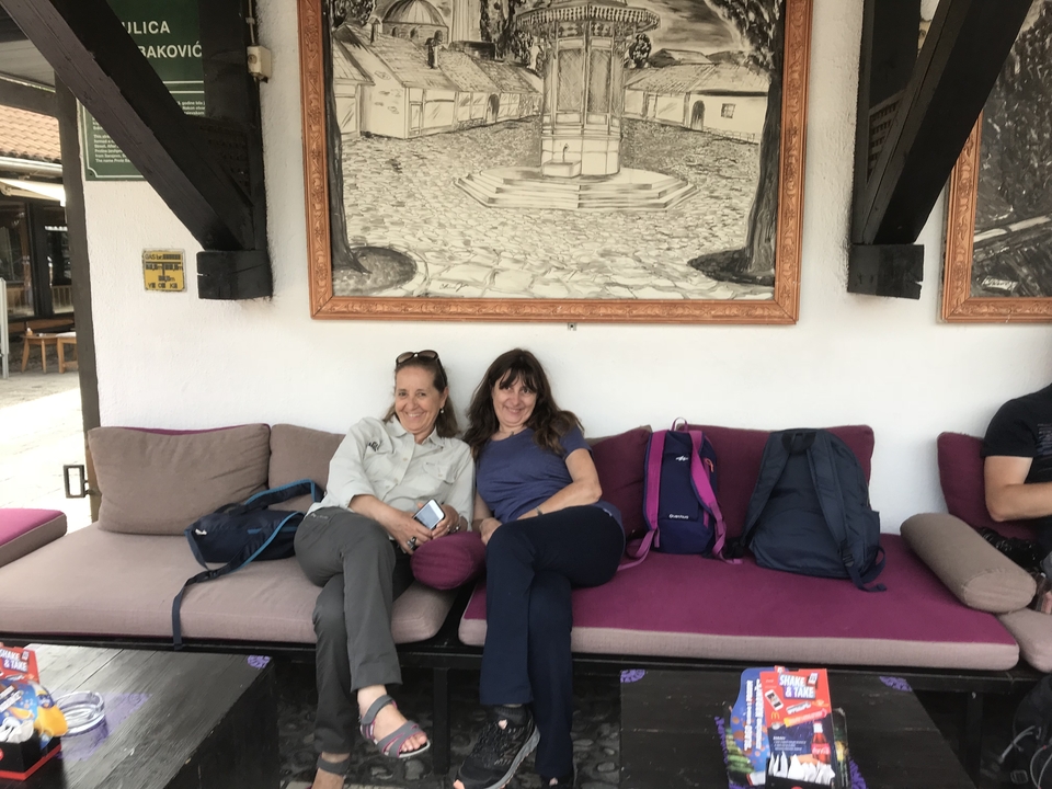 Deux femmes assises sur un banc rembourré en plein air.