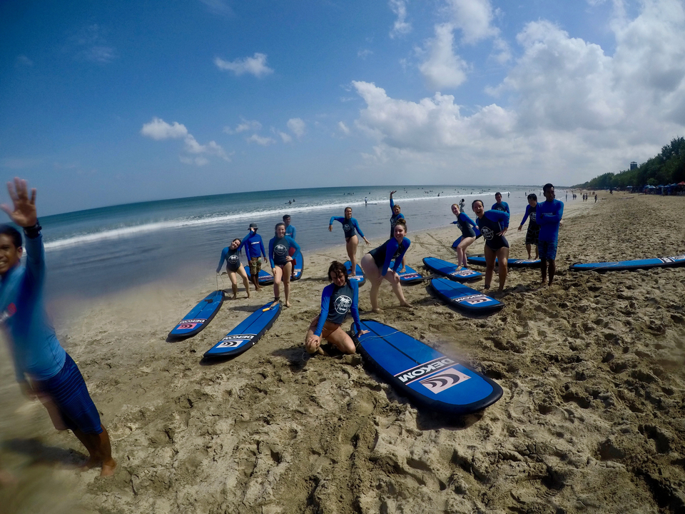 A group of people engaging in a surfing lesson on a beach.
