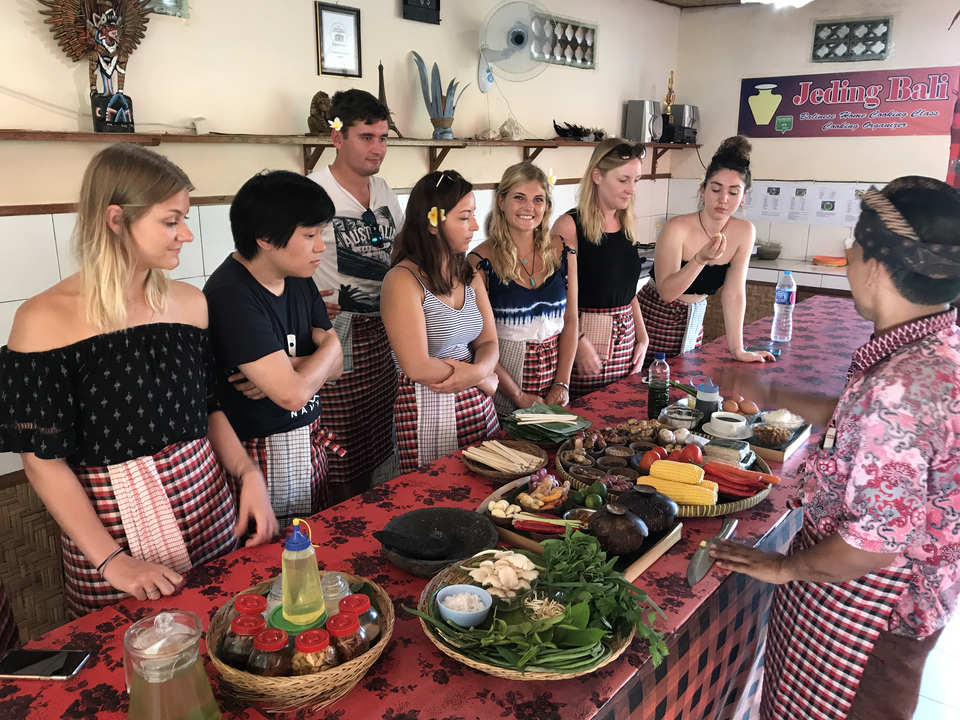 A cooking class with participants and a table full of ingredients.