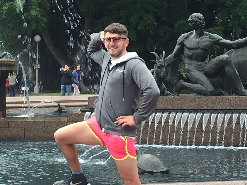 A person posing confidently in front of a fountain.