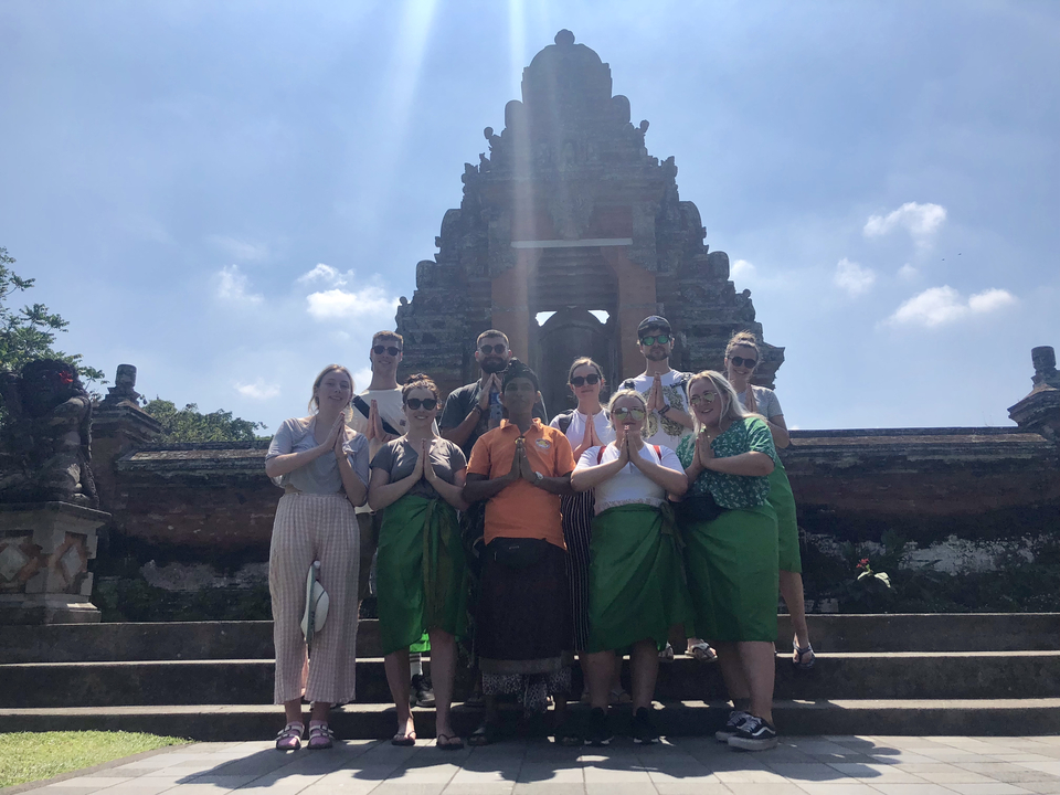 Group of people in traditional clothing in front of a temple.