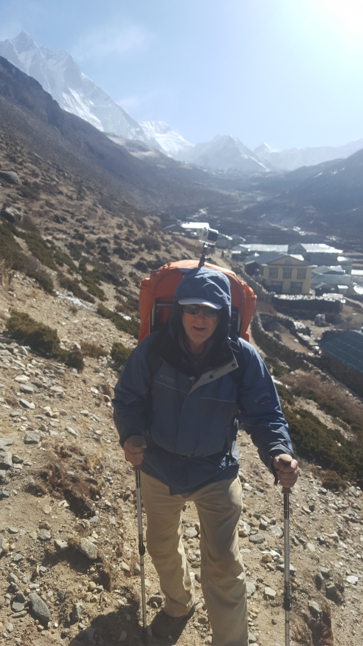 Hiker with backpack and sunglasses on a rocky path.