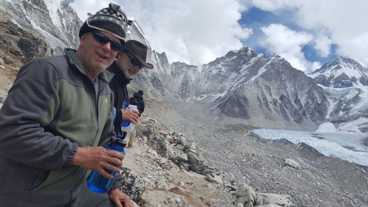 Two people posing with water bottles in front of a mountain range.