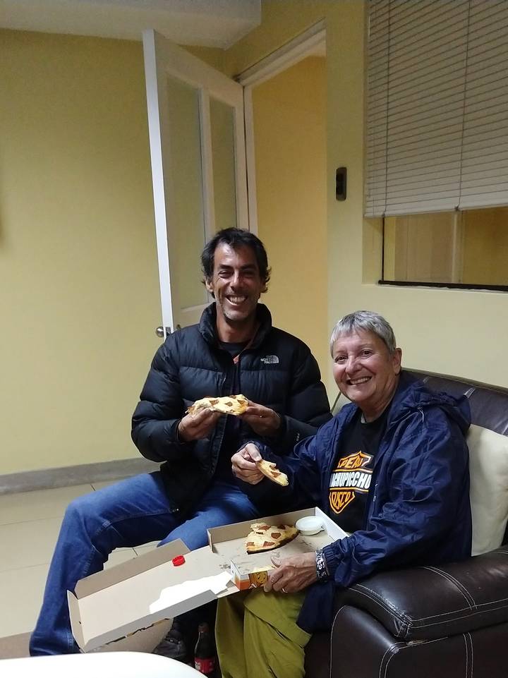 Two people sitting indoors and enjoying food.