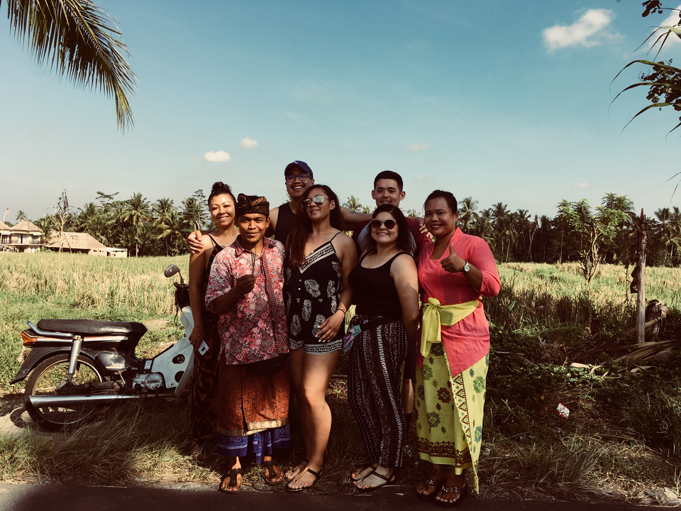 Group of people standing together in a field with palm trees in the background.