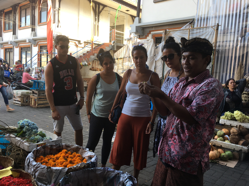 Group of people listening to a local guide at a market.