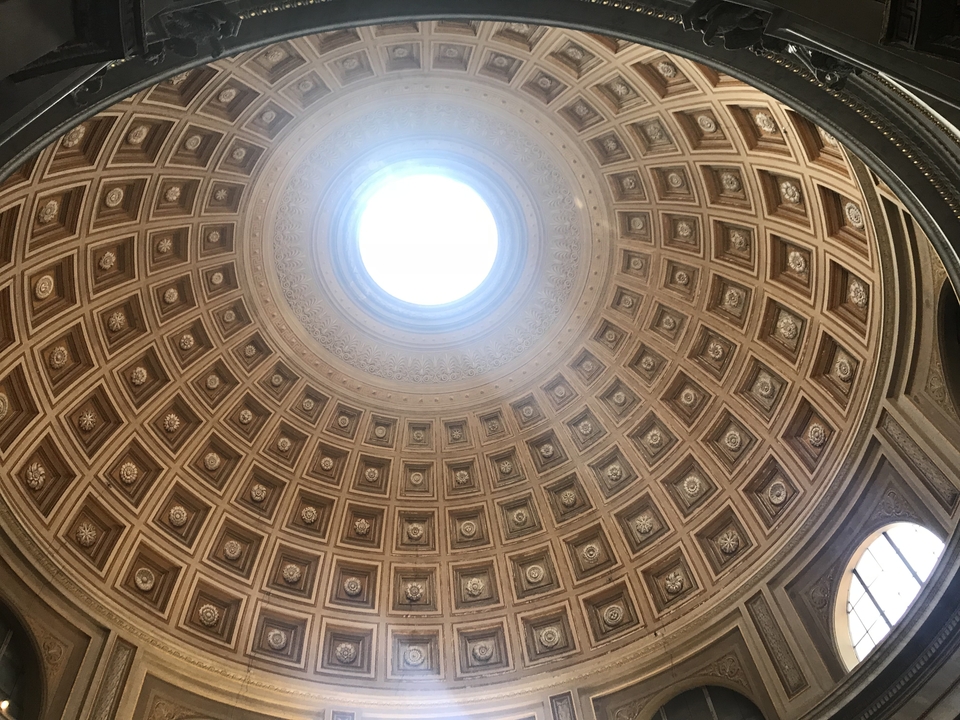 Ceiling with ornate circular design and natural sky light.