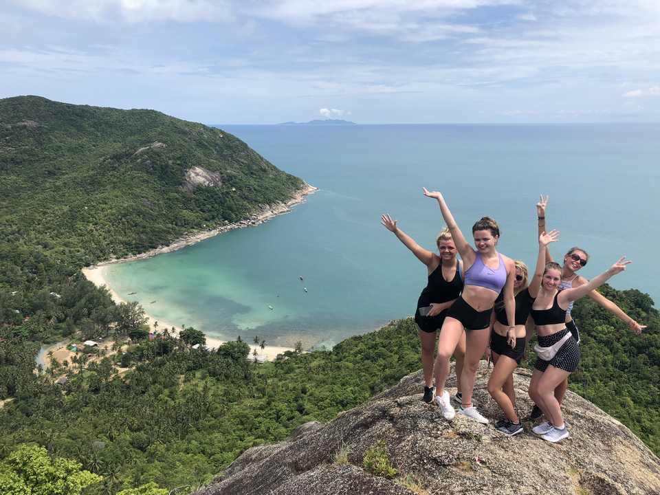 Group of people posing happily with a bay view in the background.