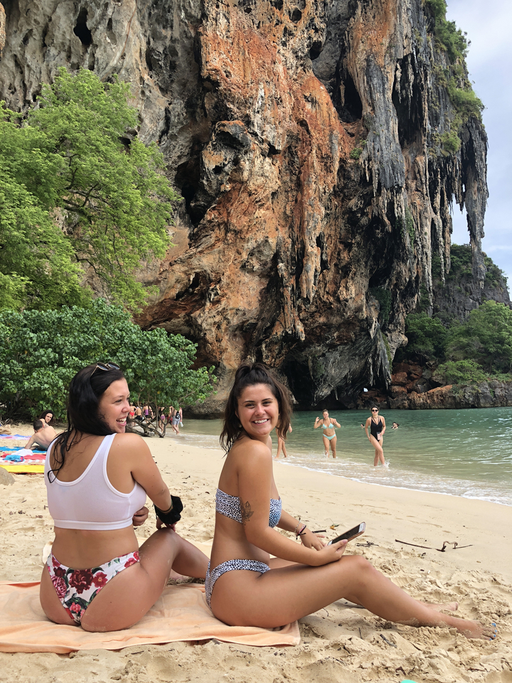 People enjoying the beach near a large rock formation.