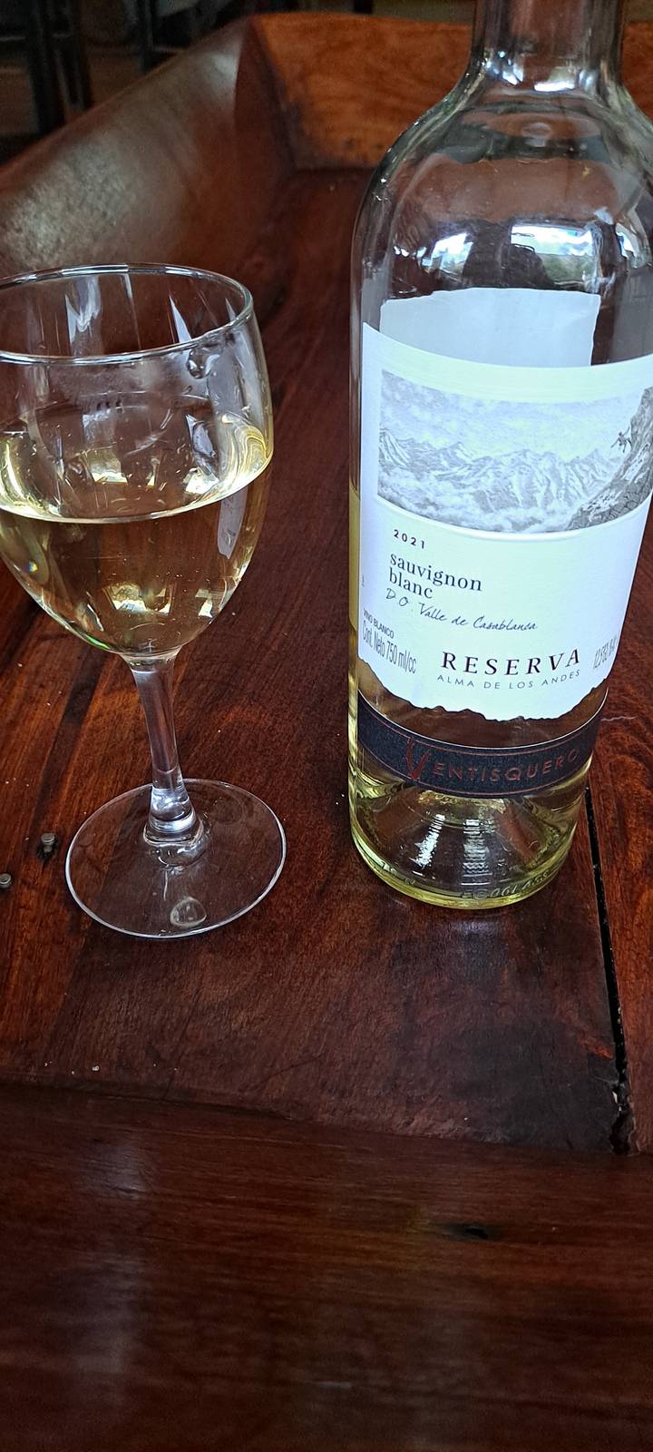 A bottle of wine and glass on a wooden surface.