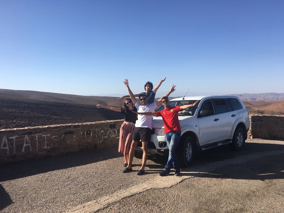 Group of friends posing by a car in the desert