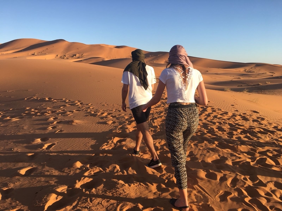Two people walking on sand dunes
