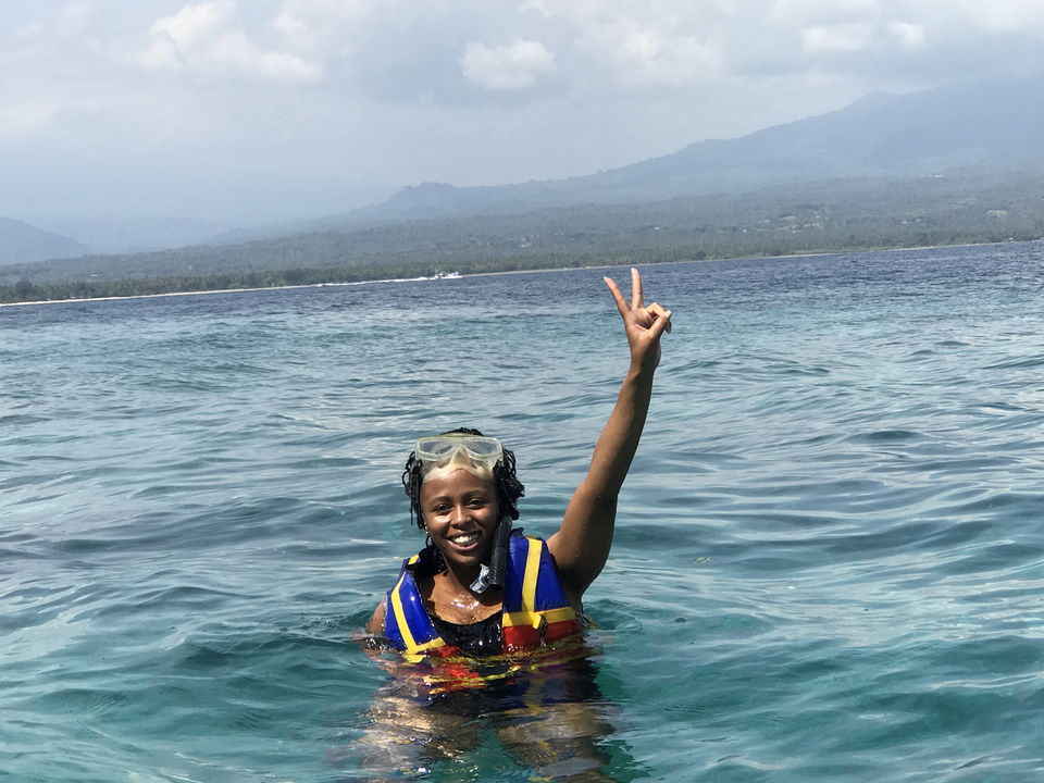 Person enjoying a swim in the ocean, smiling and wearing snorkeling gear.