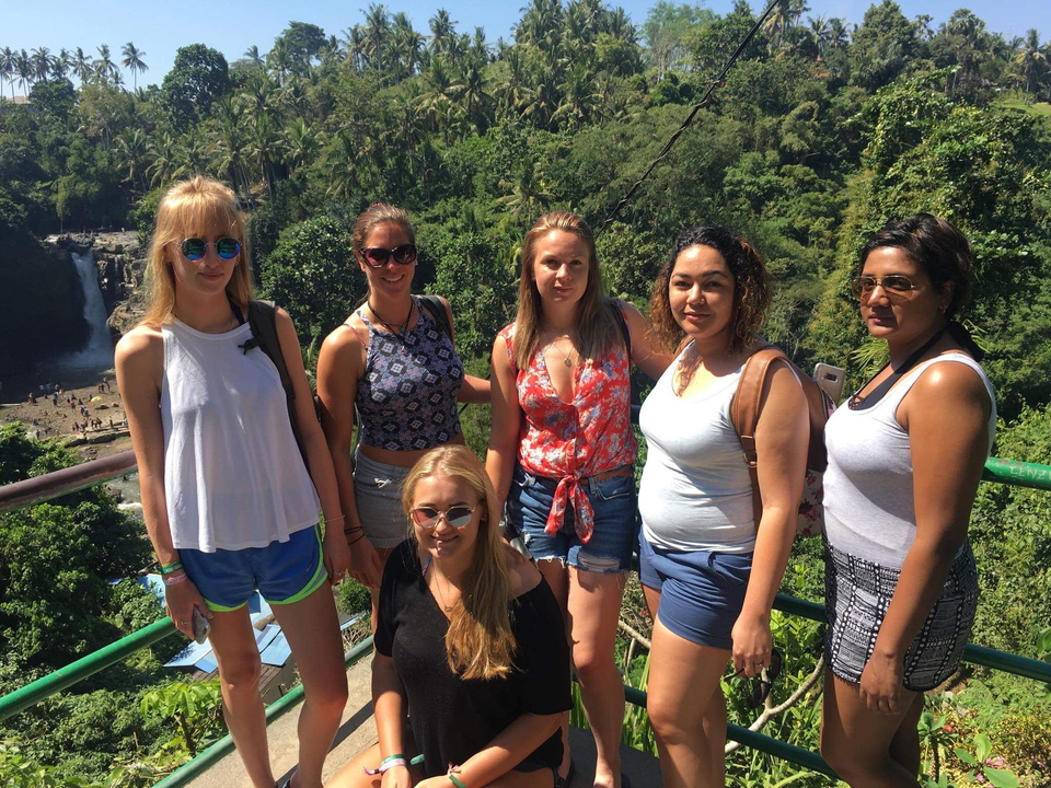 Six women posing at a viewpoint overlooking a waterfall.