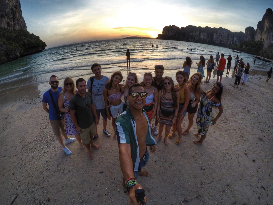 Group of people posing on a beach during sunset.