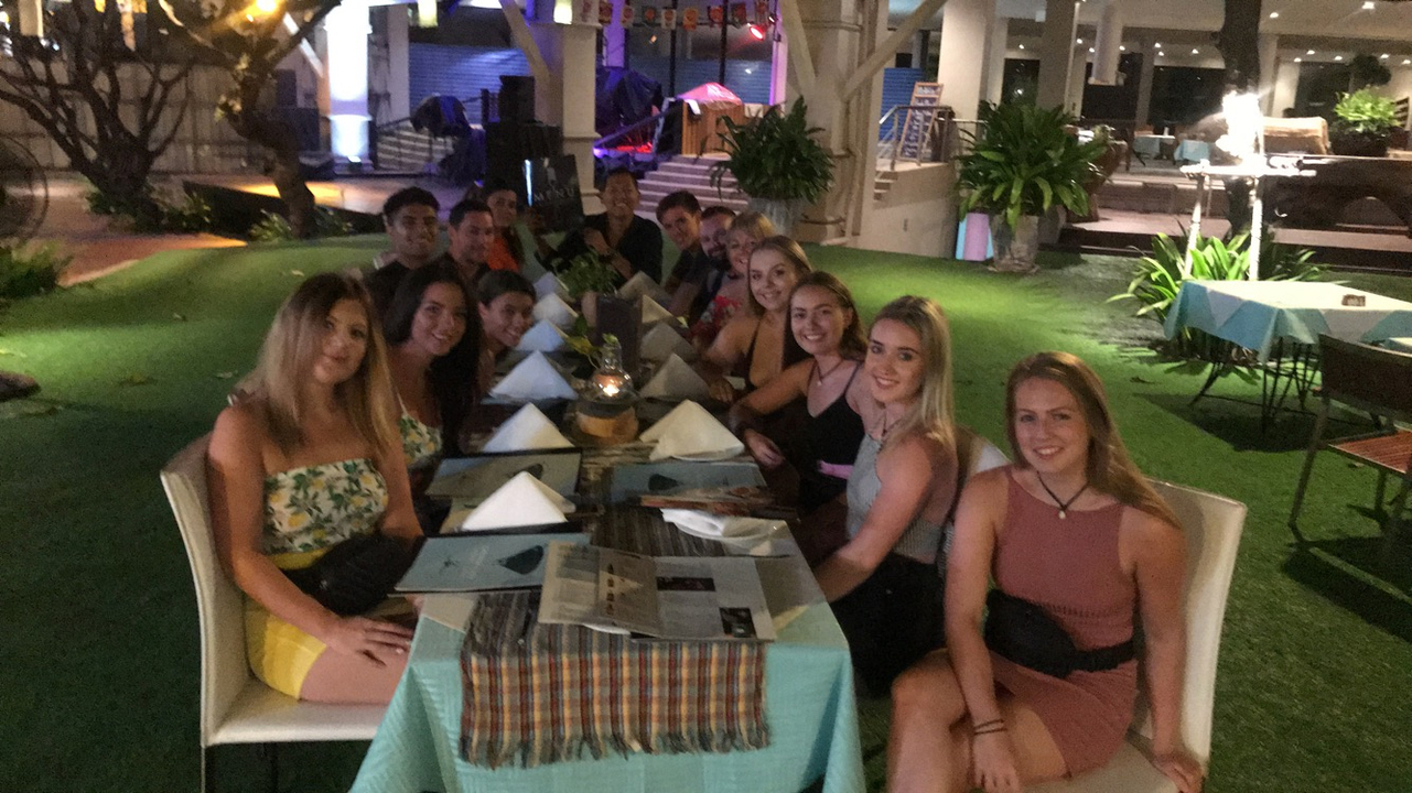 Group of people dining outdoors in a resort setting at night.