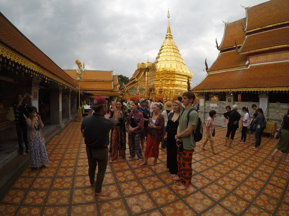 Visitors posing in front of a golden pagoda and traditional architecture.