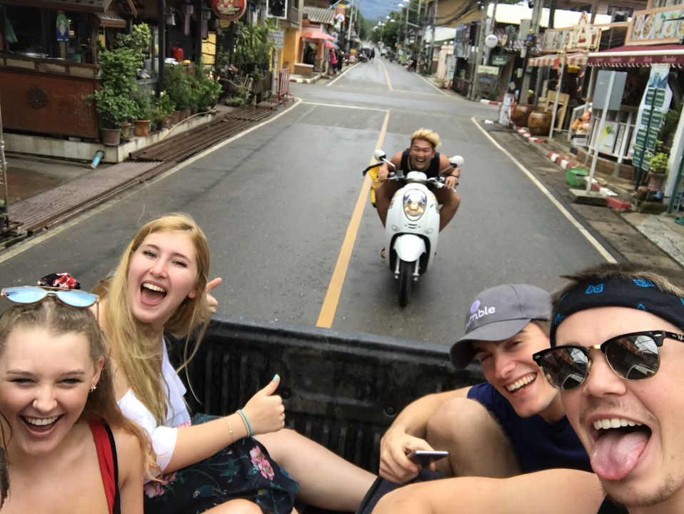 Group of people smiling and waving as a motorbike approaches.