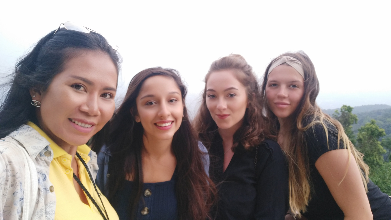 Four women posing outdoors with a scenic view.