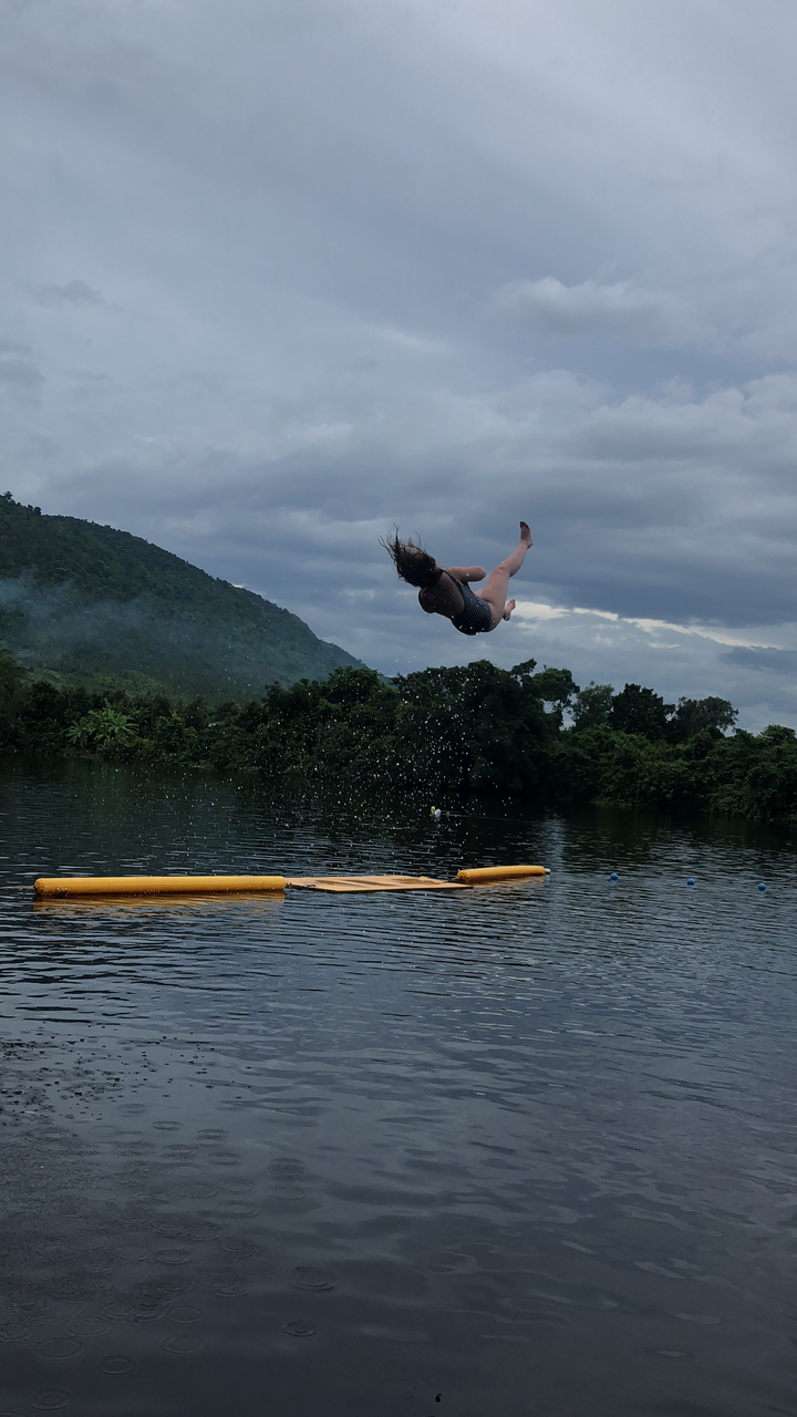 Person midair during a water jump in a scenic area.