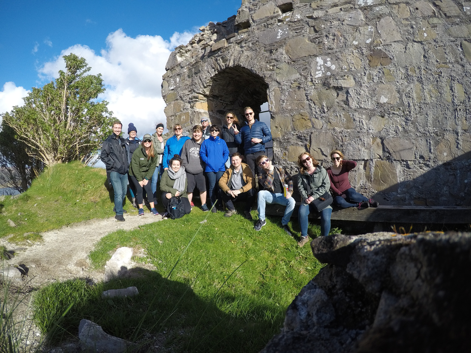 Group in front of a stone ruin with grassy landscape.