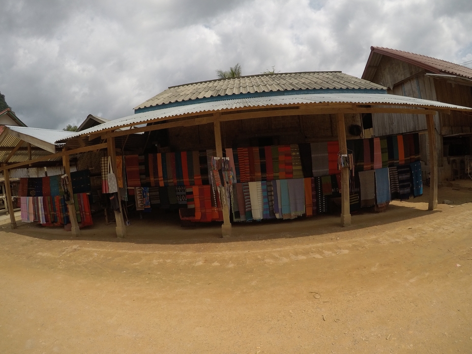 Traditional textiles displayed on a wooden building in a village.