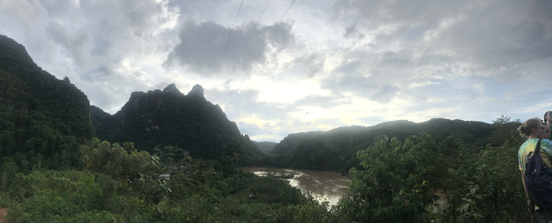 River flowing through a valley with mountains and clouds.