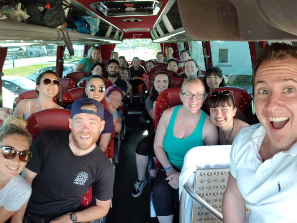 Group of people on a bus smiling at the camera.