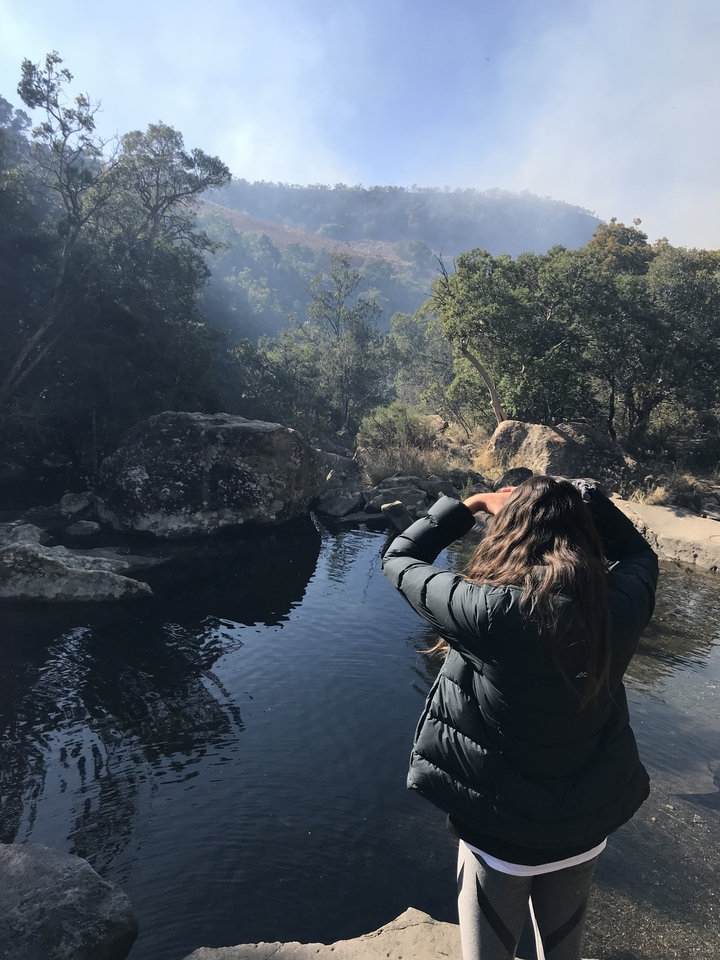 Personne regardant vers un petit étang avec des rochers autour.
