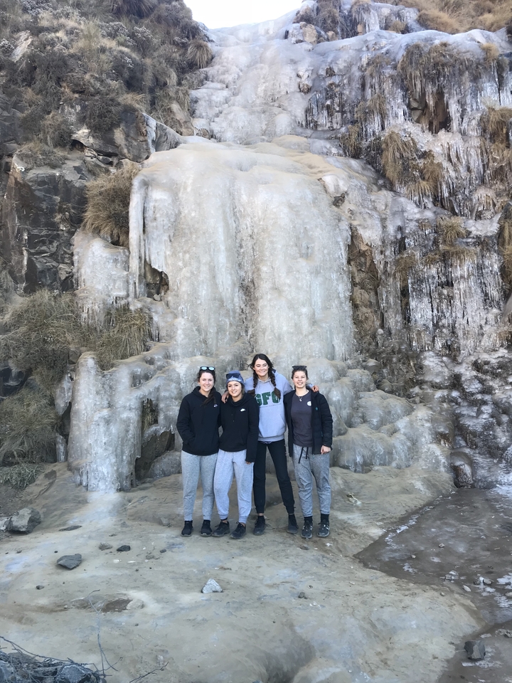 Groupe de personnes posant devant une cascade gelée.