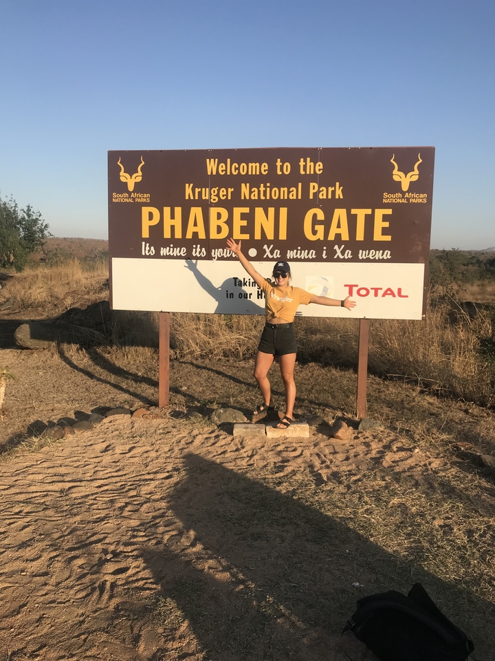 Personne posant avec un panneau Phabeni Gate dans un parc.