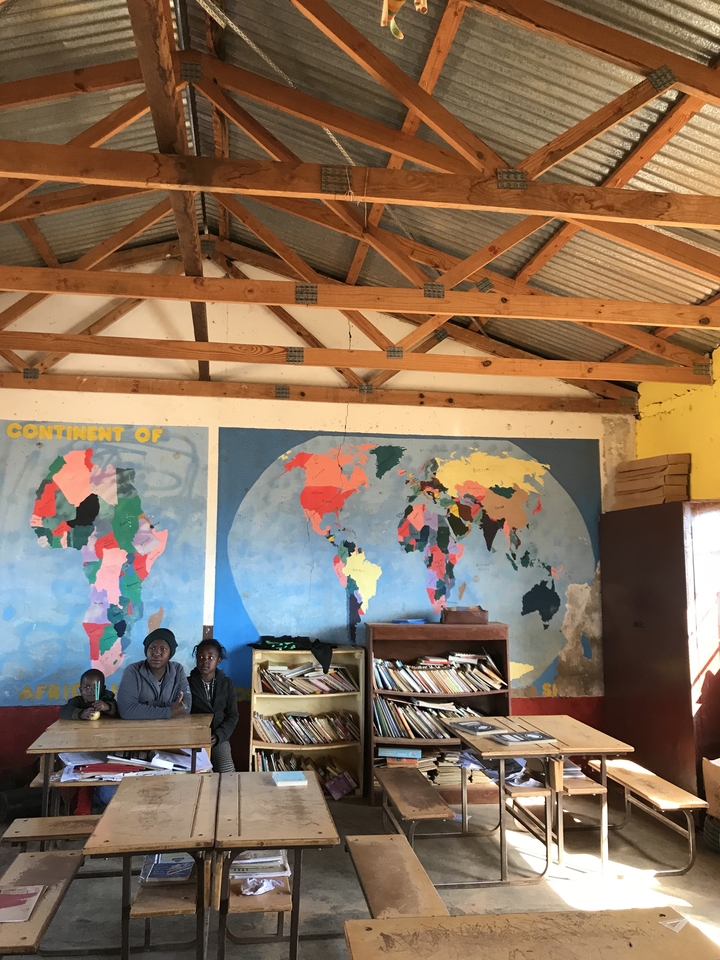 Deux personnes assises dans une pièce avec des cartes du monde au mur.