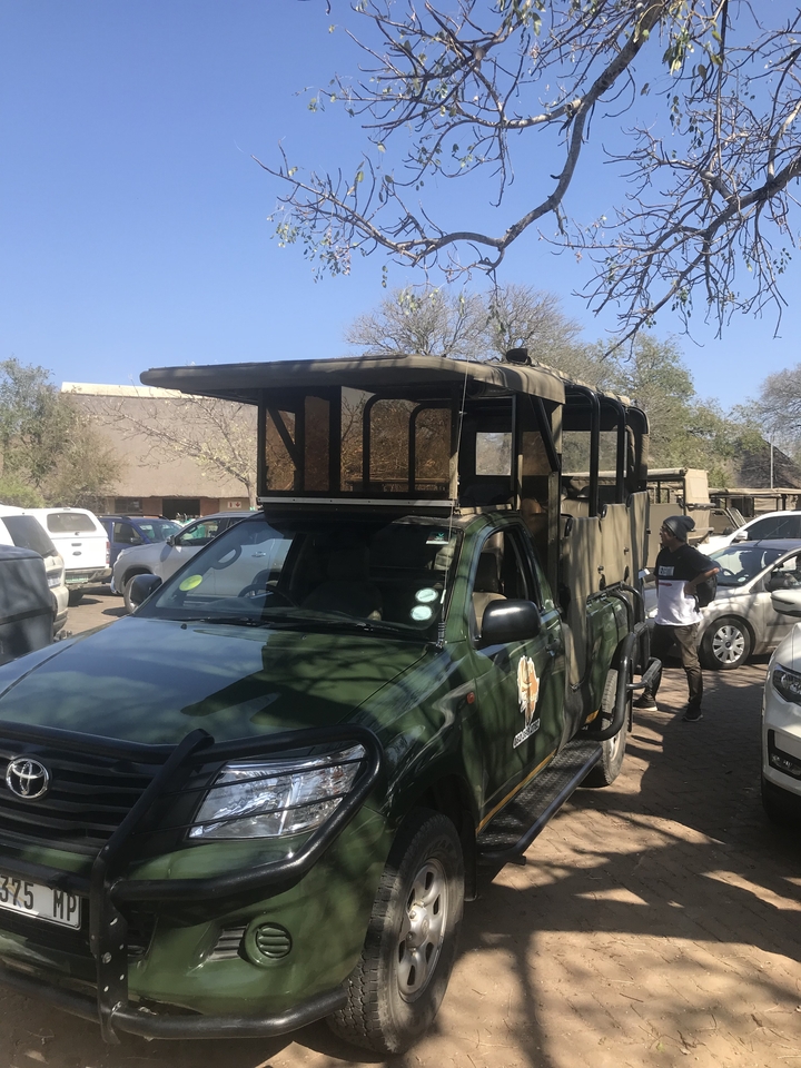 Un véhicule de safari garé sur un terrain avec une personne à côté.