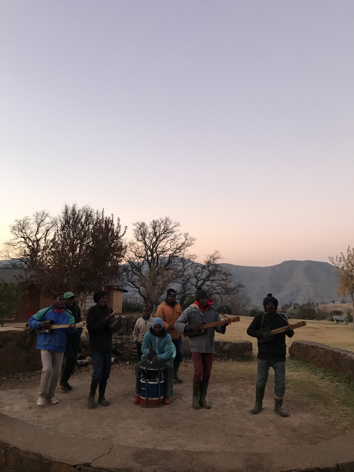 Groupe de personnes jouant de la musique au crépuscule avec la montagne en toile de fond.