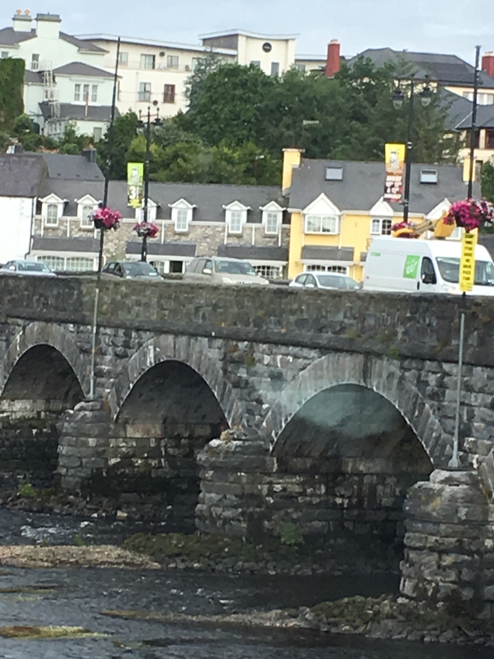 An old stone bridge over a river in a town.