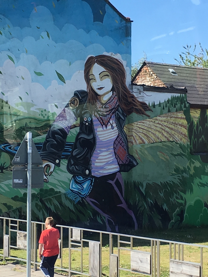 A mural of a woman in a leather jacket in a rural setting.
