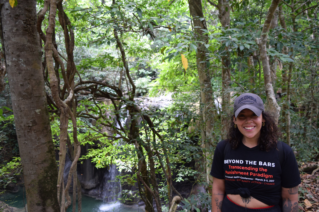 Person posing in a forest with waterfall background.