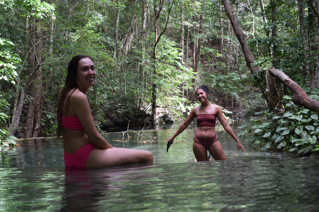 Two women in swimwear in a natural pool.