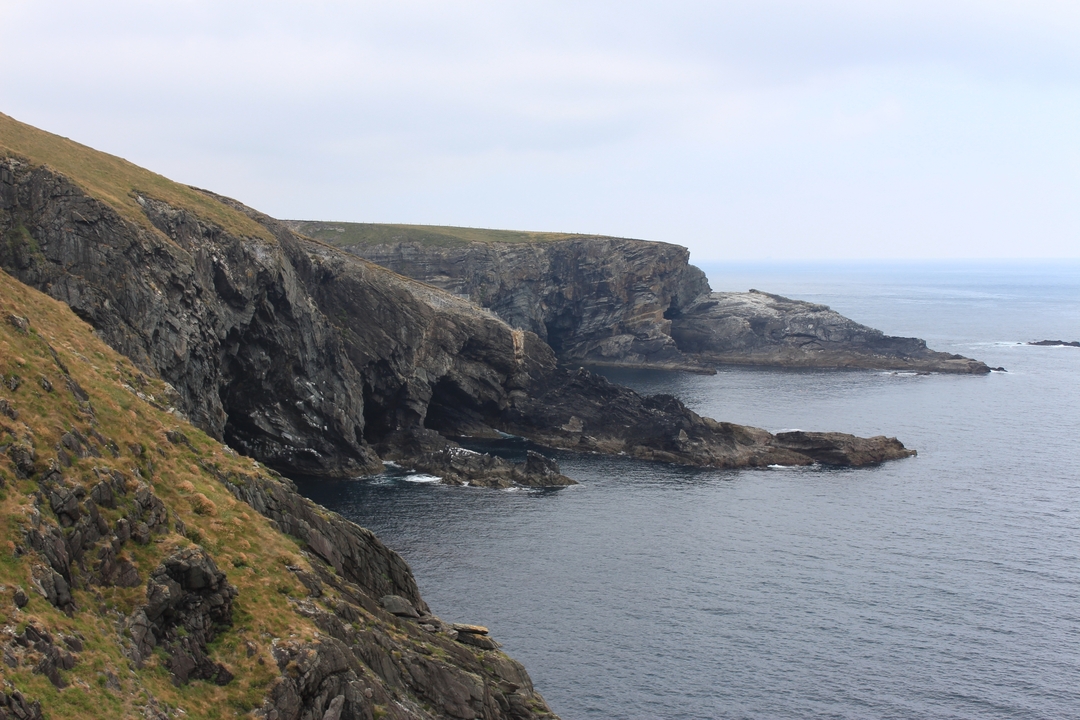 Rocky cliffs beside a calm sea.