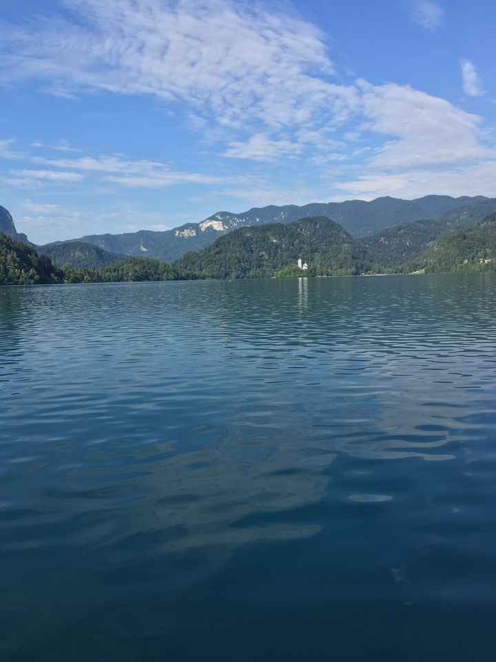 Tranquil lake with rolling hills and a distant building.