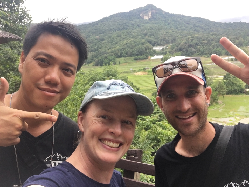 Individuals posing in front of a lush green backdrop.