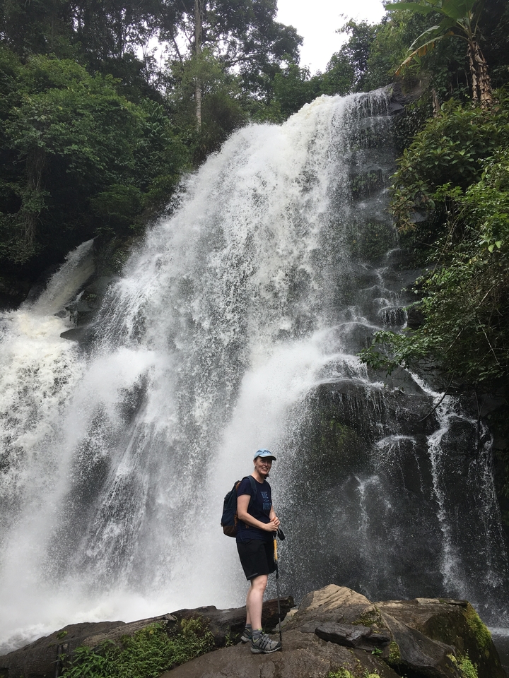 Waterfall cascading over rocks with a person standing at the base.