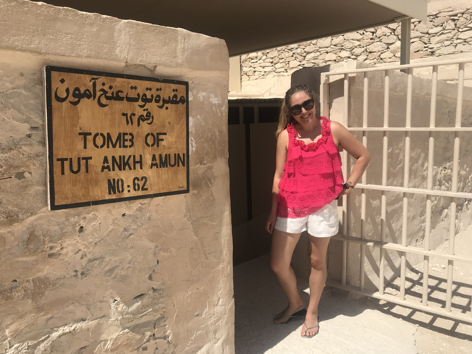 Visitor standing next to a sign marking the Tomb of Tutankh Amun entrance.