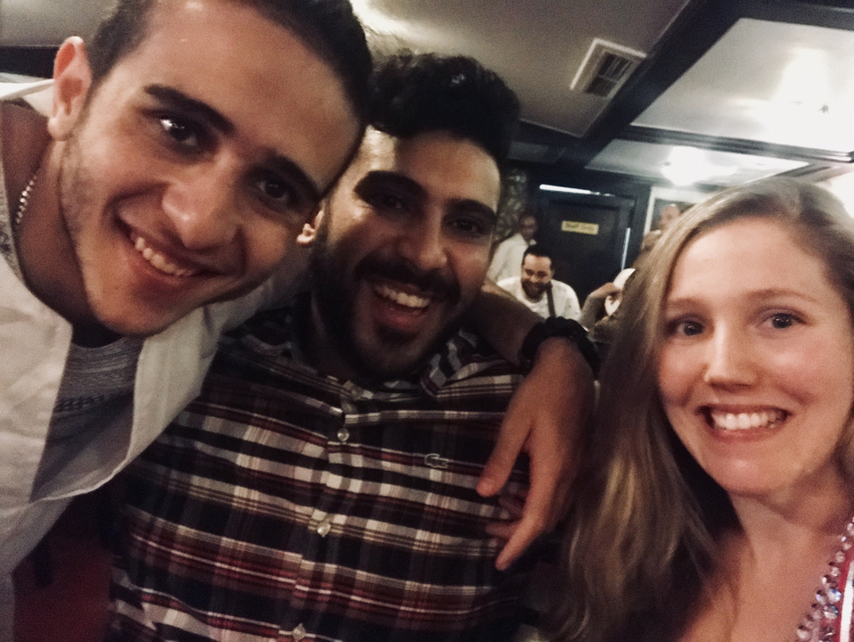 Close-up selfie of three friends smiling inside a dimly lit venue.