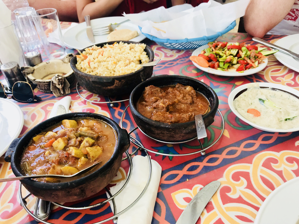 Egyptian dishes laid out on a colorful patterned tablecloth ready for a meal.