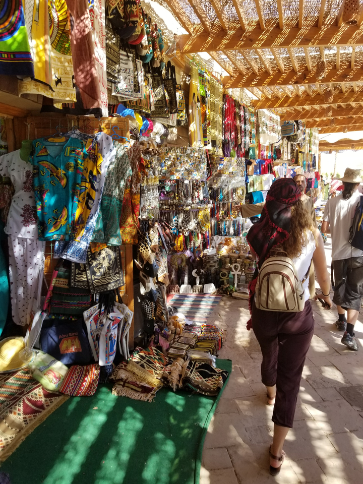 Busy market with colorful textiles and souvenirs.