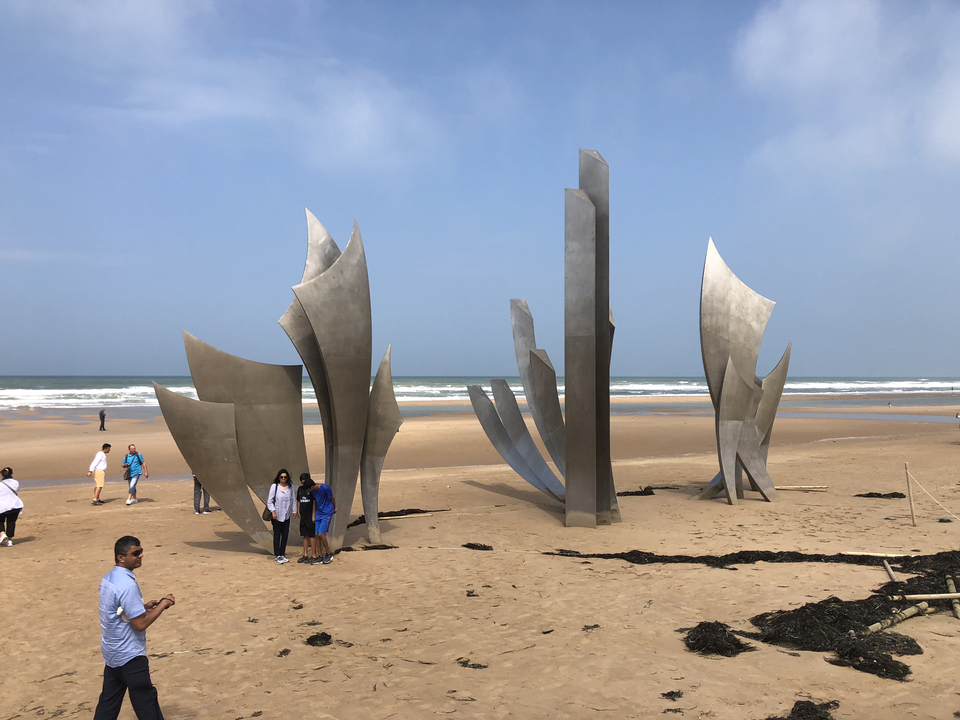 Monument sur la plage avec des gens autour.